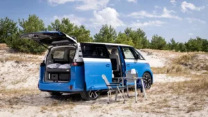 Blå Volkswagen ID. California Cruise med åben bagklap, seng, bord og campingstole