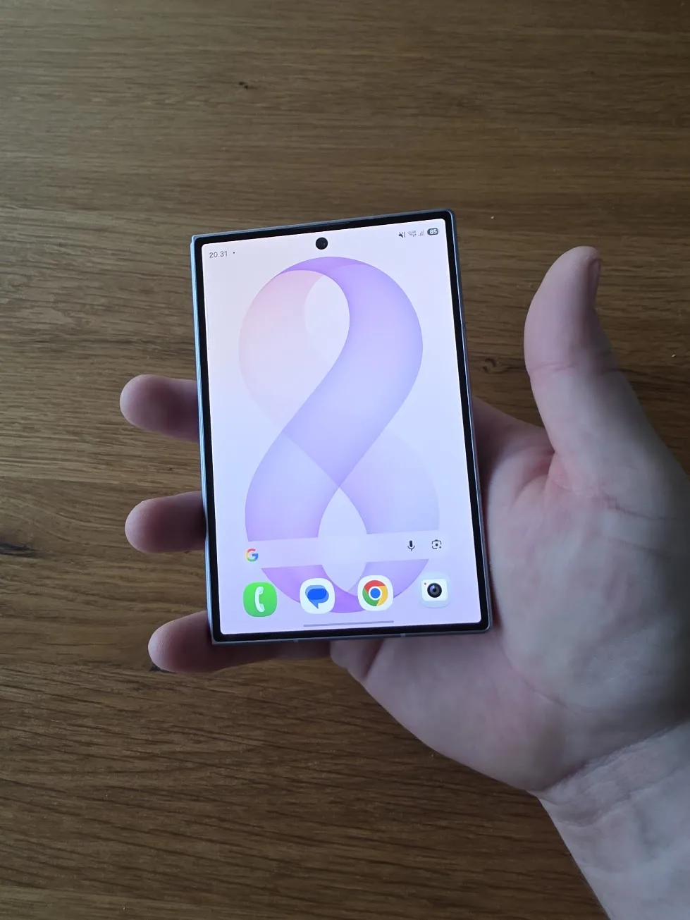 Samsung Galaxy Z Fold8 foldet sammen i en hånd med frontskærmen tændt