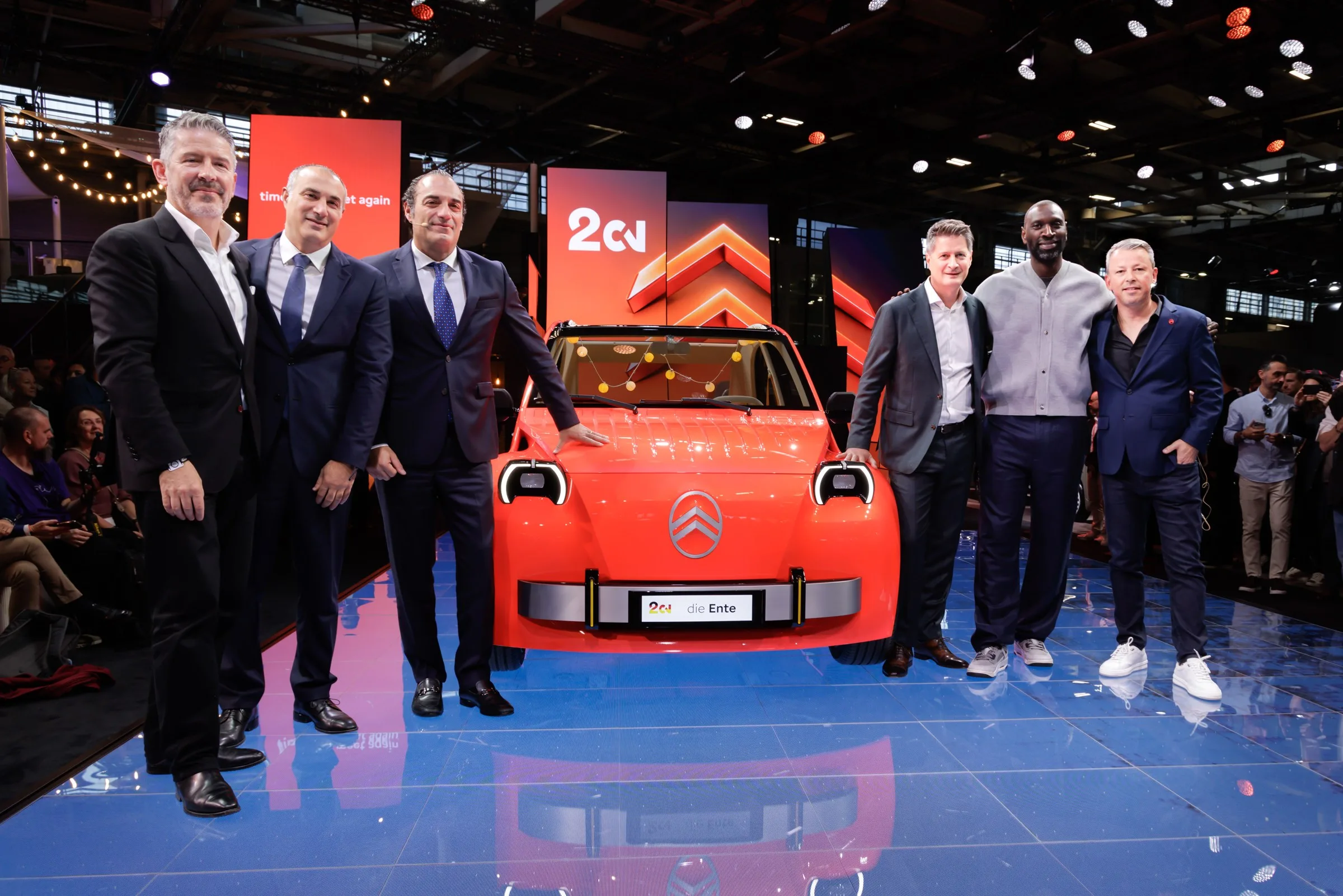 Gruppe ved den orange Citroën 2 CV Concept på standen i Paris